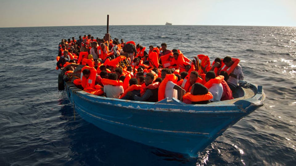 Dichtgedrängt sitzen Migranten und Migrantinnen aus Somalia und Eritrea in einem Flüchtlingsboot nahe der libyschen Küste.