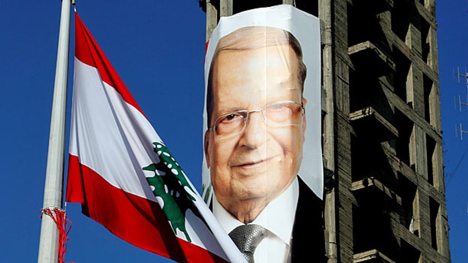 Die libanesische Flagge mit der Zeder weht vor einem Wahlplakat mit dem Bild von Michel Aoun.