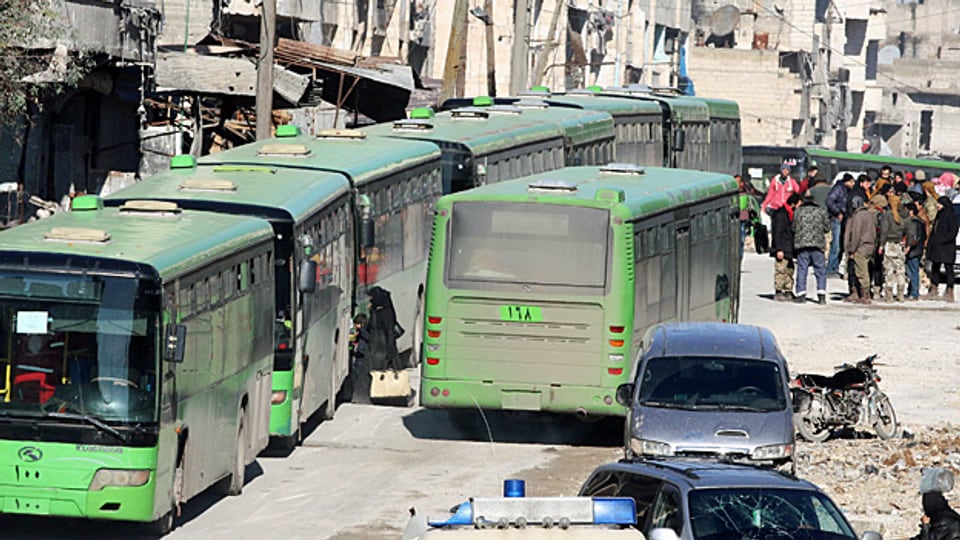 Menschen versammeln sich im Osten Aleppos bei den Bussen, mit denen sie aus der Stadt gebracht werden sollen.