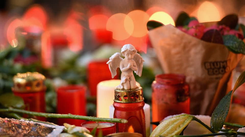 Im Gedenken an die getöteten und verletzten Menschen liegen auf dem Weihnachtsmarkt am Breitscheidplatz in Berlin Kerzen und Blumen
