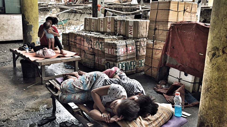 Am Rande der Markthalle im Slum auf der philippinischen Insel Cebu schläft ein junges Paar eng aneinander geschmiegt auf einem Feldbett.