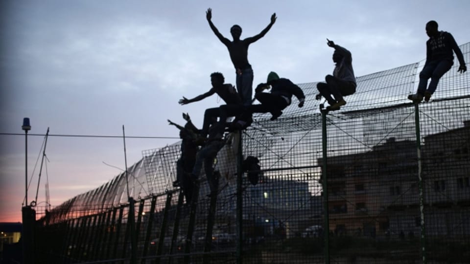 Flüchtlinge klettern über den Grenzzaun der spanischen Enklave.