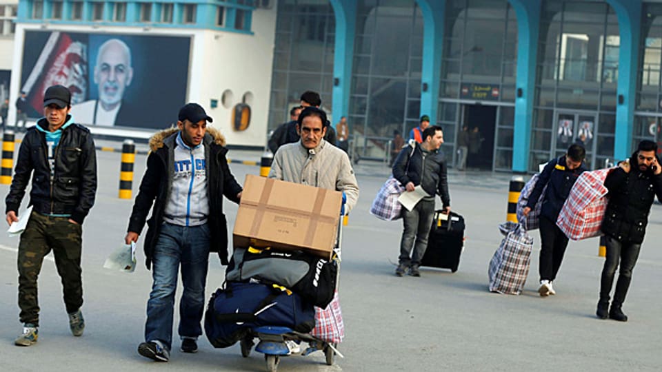 Eine Gruppe aus Deutschland zurückgeschaffter Afghanen steht mit Koffern und Taschen vor dem Flughafengebäude der afghanischen Hauptstadt Kabul.
