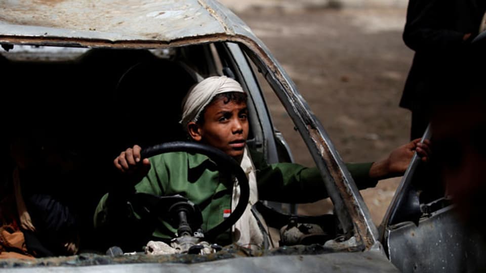 Ein Junge spielt in einem zerbombten Auto im Hof der Al-Shawkani-Stiftung für Waisenpflege in Sanaa, Jemen.