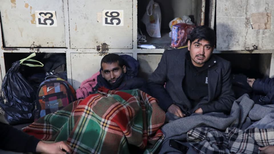 Migranten in Decken in einem verfallenen Zolllager in Belgrad, Serbien.