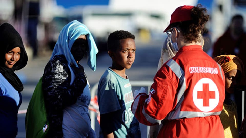 Eine Mitarbeiterin des italienischen Roten Kreuzes betreut neu angekommene Flüchtlinge.