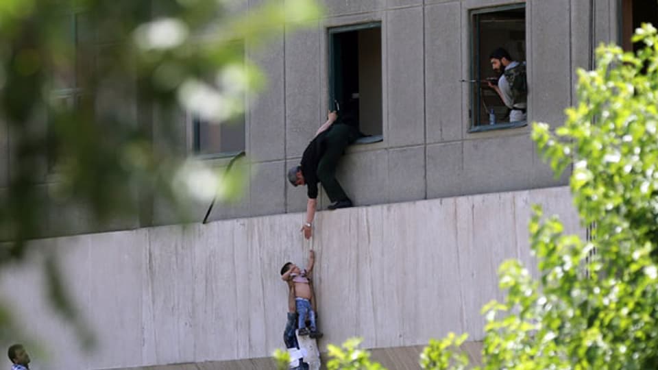 Iranische Polizisten versuchen, Zivilisten zu helfen, aus dem Parlamentsgebäude zu fliehen während des Angriffs in Teheran am 7. Juni 2017.