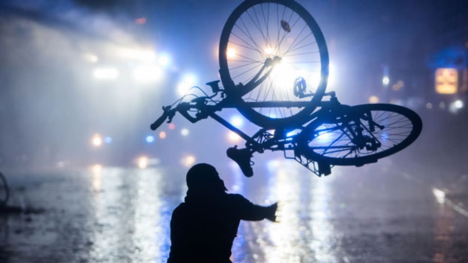 Ein Randalierer wirft am 09.07.2017 in Hamburg im Schanzenviertel ein Fahrrad in Richtung von Wasserwerfern.