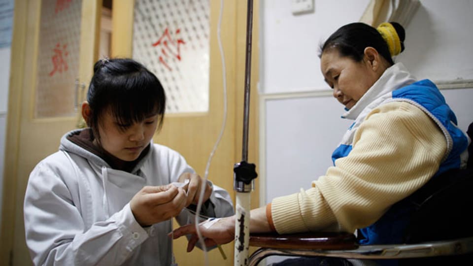 Immer häufiger werden chinesische Ärzte von Patienten oder ihren Familien angegriffen. Grund dafür sind Mängel im Gesundheitswesen.Bild: Eine Krankenschwester behandelt eine Patientin in einer Klinik in Peking.