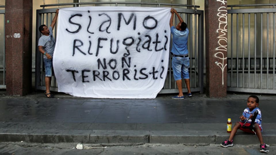Nach der Hausräumung in Rom hängen Flüchtlinge ein Transparent auf.