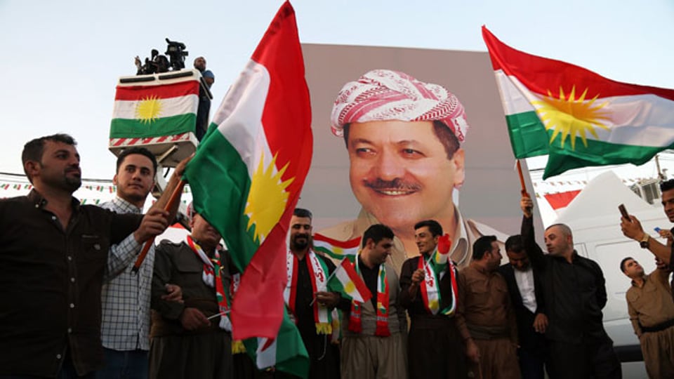 Kurdische Männer mit einem Portrait von Masaud Barzani, dem Präsidenten der kurdischen Autonomiezone.
