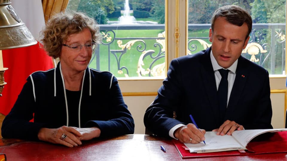 Der französische Präsident Emmanuel Macron unterzeichnet eine neue Verordnung. Links ist Arbeitsministerin Muriel Penicaud.