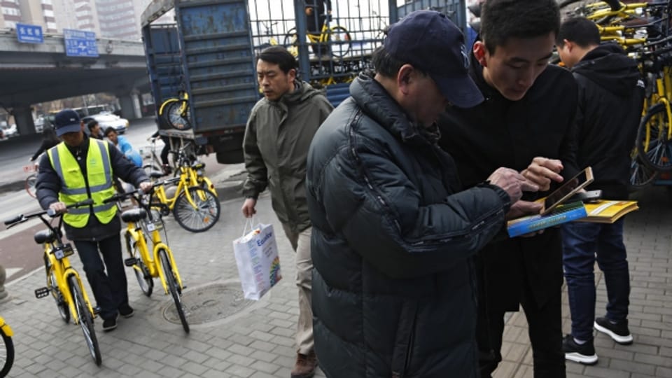 Ein Interessierter lässt sich in Peking darüber informieren, wie die Velo-Miete funktioniert