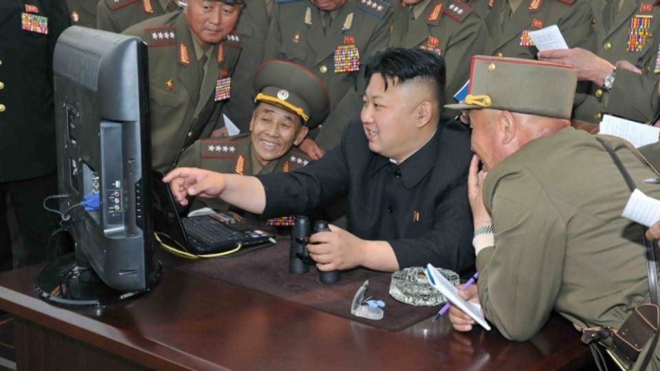 Der nordkoreanische Diktator Kim Jong-un schaut sich mit Artillerie-Soldaten zusammen einen Computer an.