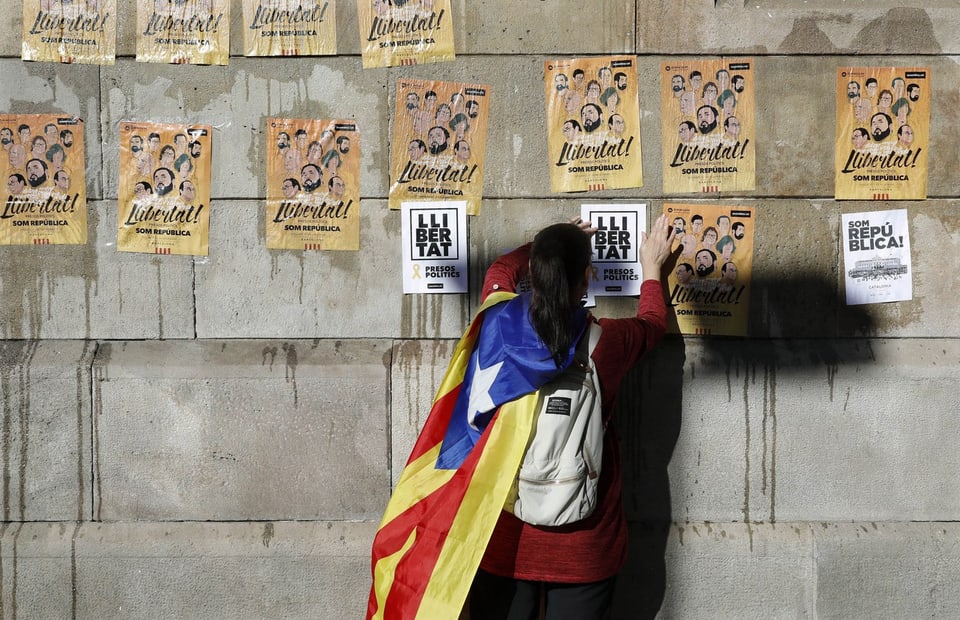 Eine Frau hängt in Barcelone Aufrufe zu einer Kundgebung auf.