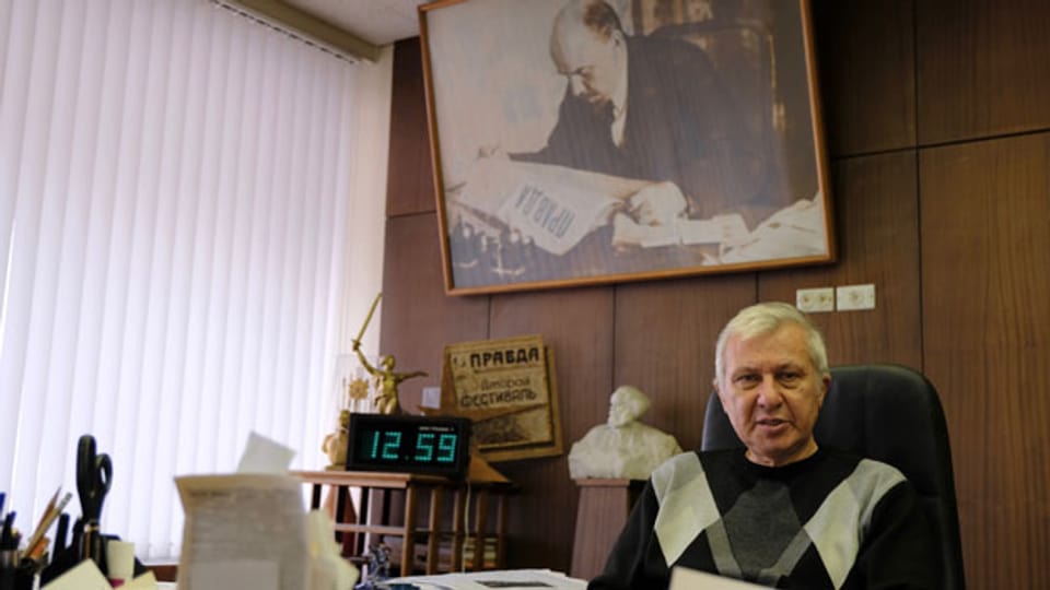 Chefredaktor Boris Komozki in seinem riesigen Büro unter einem Leninbild. Bild: David Nauer/SRF.