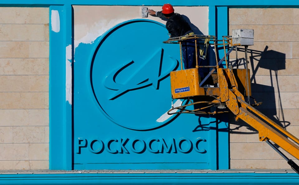 Ein kasachischer Arbeiter reinigt einen Schriftzug am Gebäude des russischen Weltraumbahnhofs Baikonur in Kasachstan
