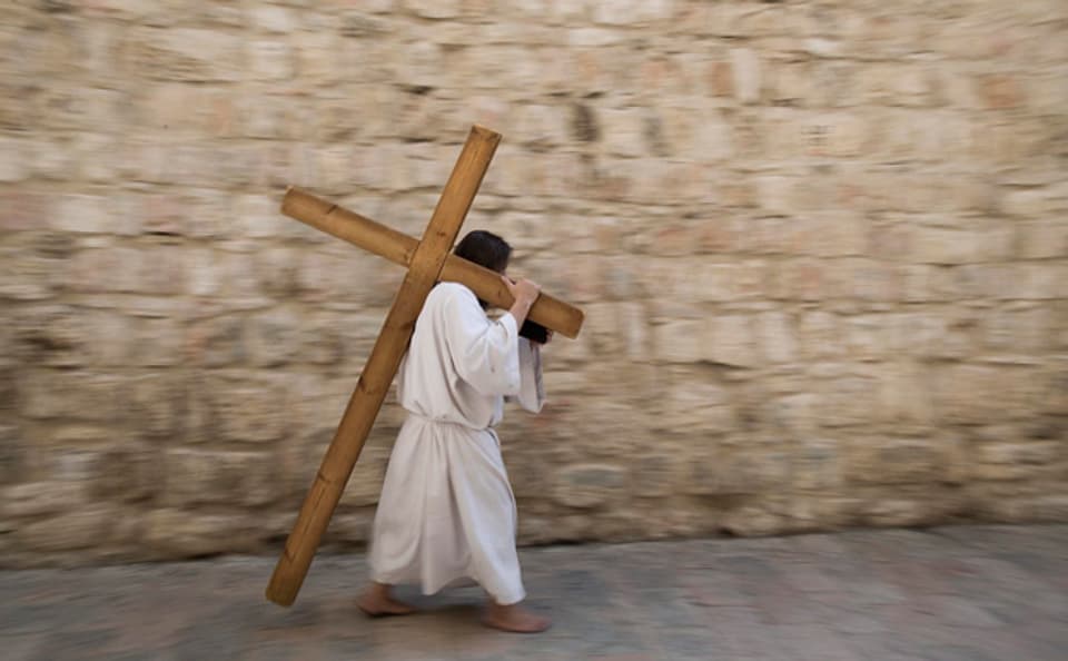 Ein christlicher Pilger trägt ein Kreuz durch die Via Dolorosa in Jerusalem.