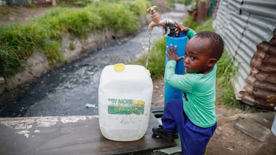 Ein Junge holt Wasser am Brunnen in Kapstadt.