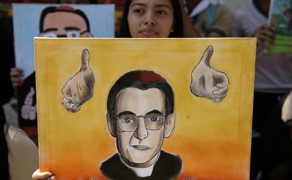 Eine Frau in San Salvador hält ein selbstgezeichnetes Portrait hoch des ermordeten Erzbischofs Oscar Romero.