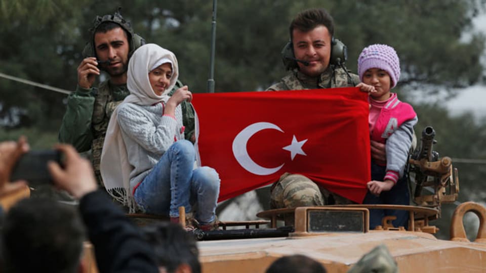 Türkische Soldaten in der Stadt Afrin und syrische Kinder, die die türkische Fahne hochheben.