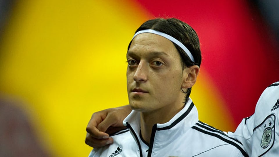 Der deutsche Fussballer Mesut Özil vor einer Deutschlandfahne. Archivaufnahme von 2012.