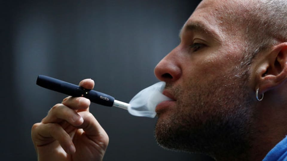 Ein Mann «dampft» eine IQOS-E-Zigarette von Philip Morris.