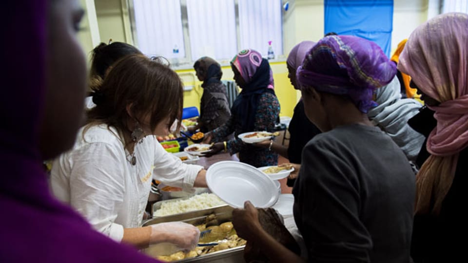 Freiwillige Helferinnen verteilen ein Essen an Flüchtlinge.