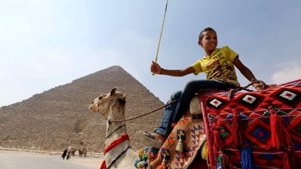 Ein Junge wartet auf seinem Kamel auf Touristen in der Nähe der Khufu-Pyramide.