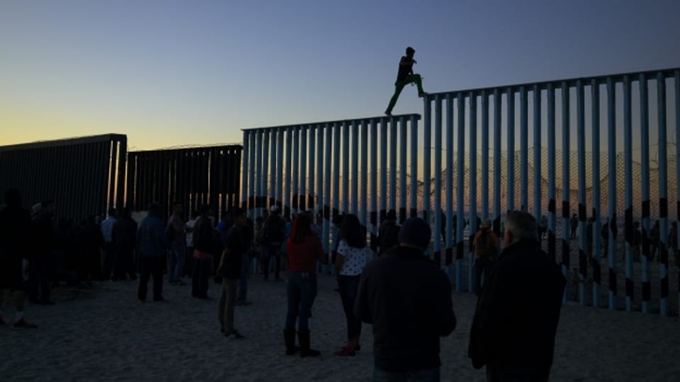 Lateinamerikanische Flüchtlinge versuchen einen Grenzzaun zu den USA zu überwinden.