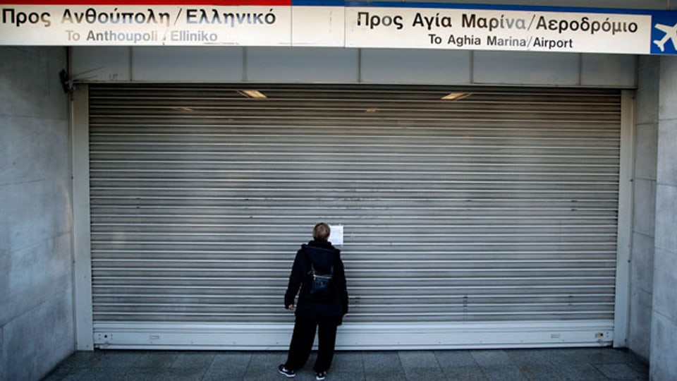 Streik in Griechenland: Eine Frau steht vor einem geschlossenen U-Bahn-Tor.