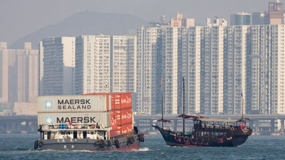 Ein Containerschiff und eine traditionelle Barkasse vor Hongkong.