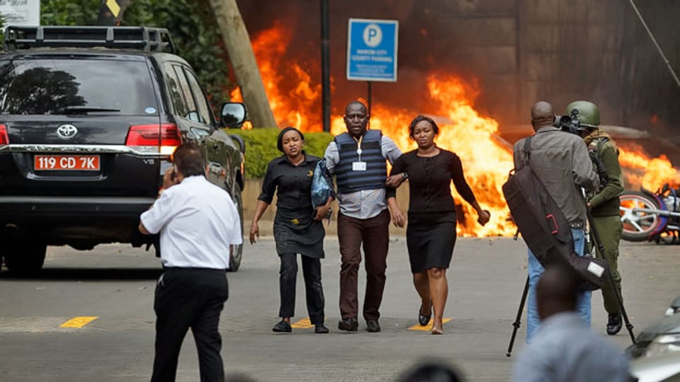 Ein Sicherheitsmann bringt nach dem Attentat auf einen Hotelkomplex in der kenianischen Hauptstadt Nairobi Zivilistinnen in Sicherheit.