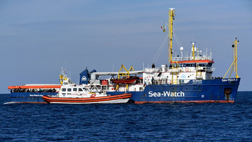 Ein Boot der Küstenwache nähert sich dem Rettungsboot Sea Watch.