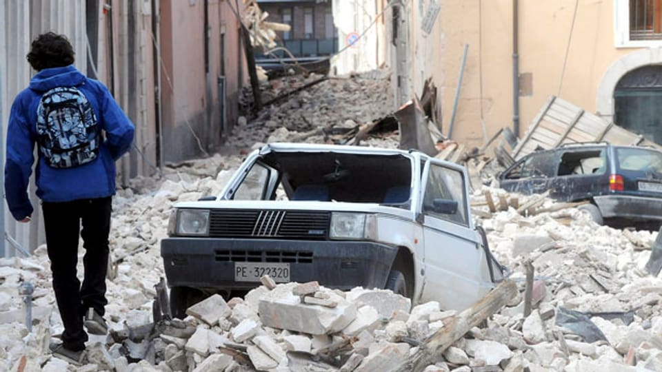 Ein Mann geht am 9. April 2009 - drei Tage nach dem Erdbeben - in L'Aquila durch Trümmer.