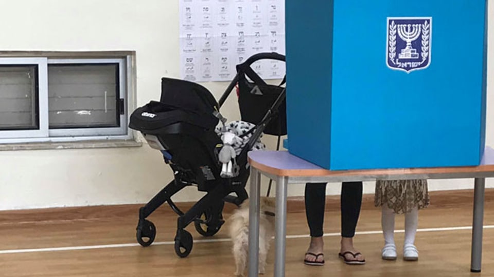 Eine israelische Stimmbürgerin zeigt ihrer Tochter, wie man in einem Wahllokal abstimmt.