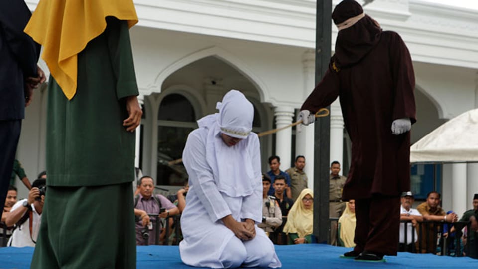 Eine Frau, die wegen sexueller Beziehungen außerhalb der Ehe gegen das Gesetz der Scharia verstossen hat, wird in Banda Aceh, Indonesien, öffentlich ausgepeitscht.