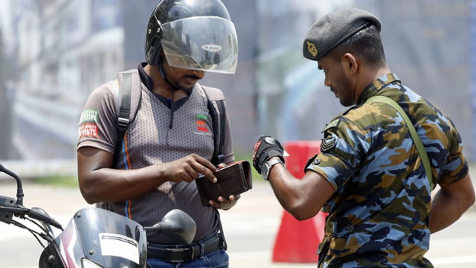 Srilankischer Sicherheitsbeamter prüft in Colombo den Identitätsnachweis eines Mannes.