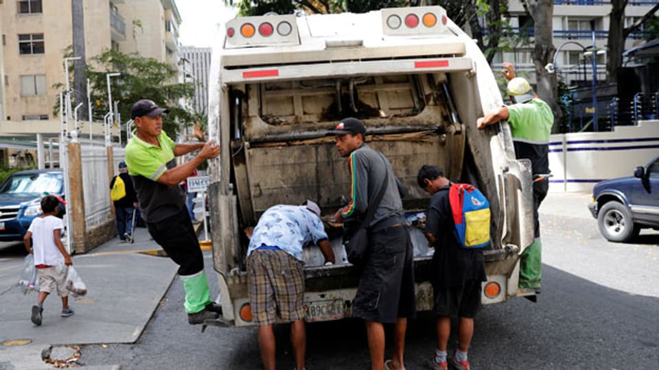 Kinder suchen nach Essen in einem Müllwagen in Caracas, Venezuela.