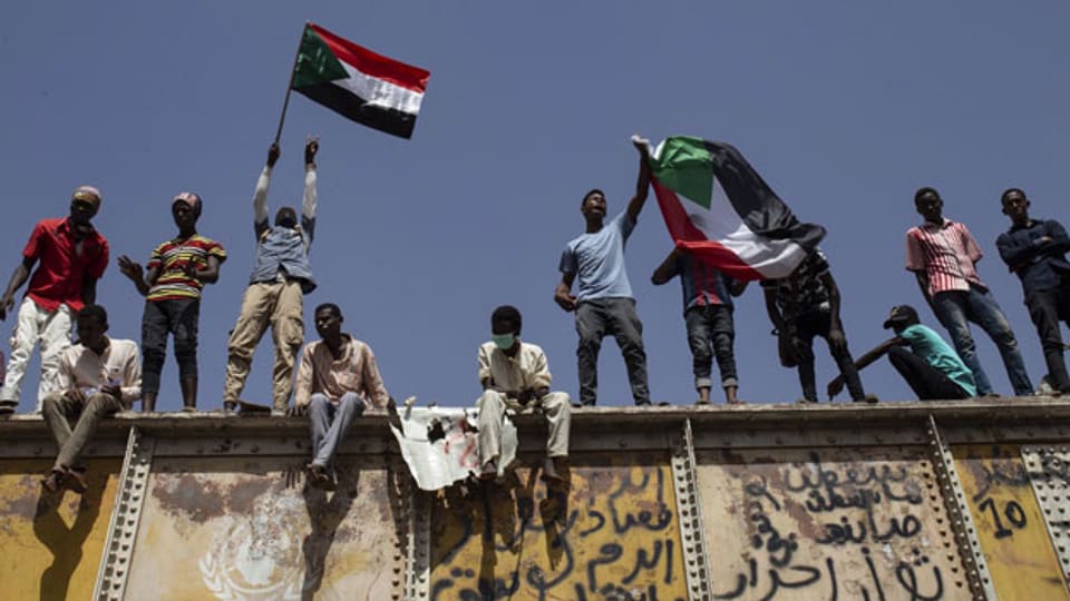 Sudanesische Demonstranten schwenken Nationalflaggen vor dem Militärhauptquartier in Khartum, Sudan.