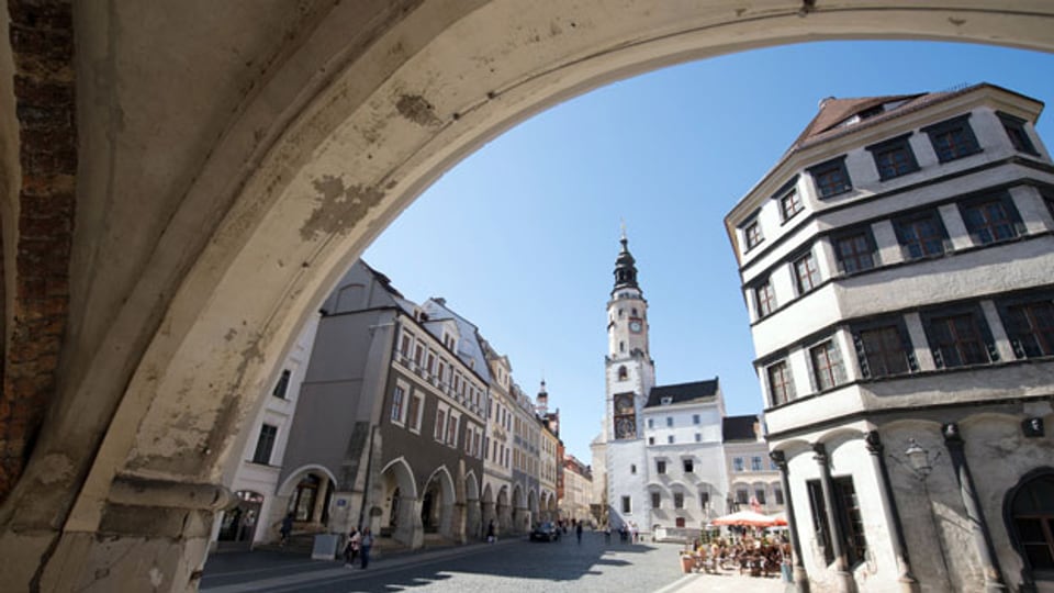 Blick durch einen Torbogen über den Untermarkt auf den Rathausturm von Görlitz.