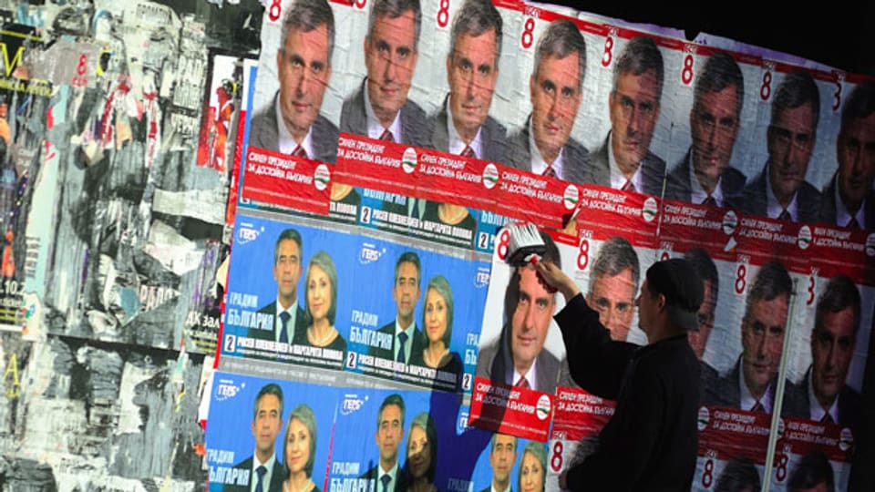 Ein Mann tapeziert eine Mauer mit Wahlplakaten.