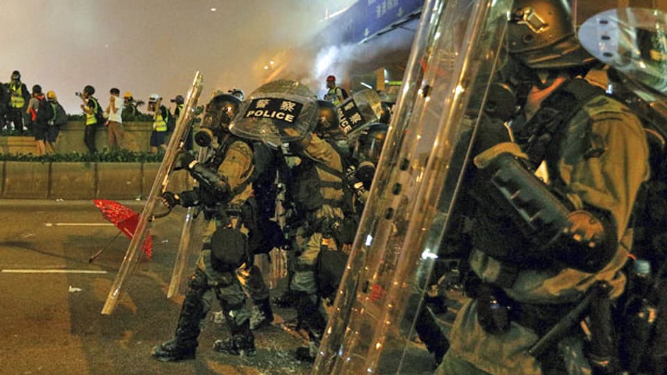 Bereitschaftspolizisten feuern auf einer Straße in Hongkong Tränengas ab.