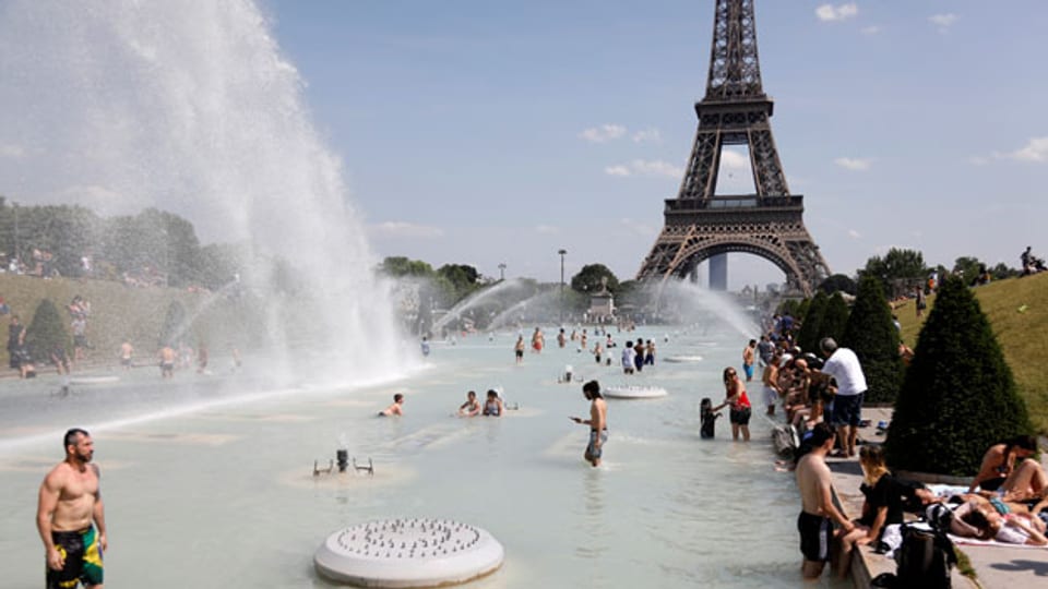 Menschen kühlen sich in den Trocadero-Brunnen gegenüber dem Eiffelturm in Paris ab.