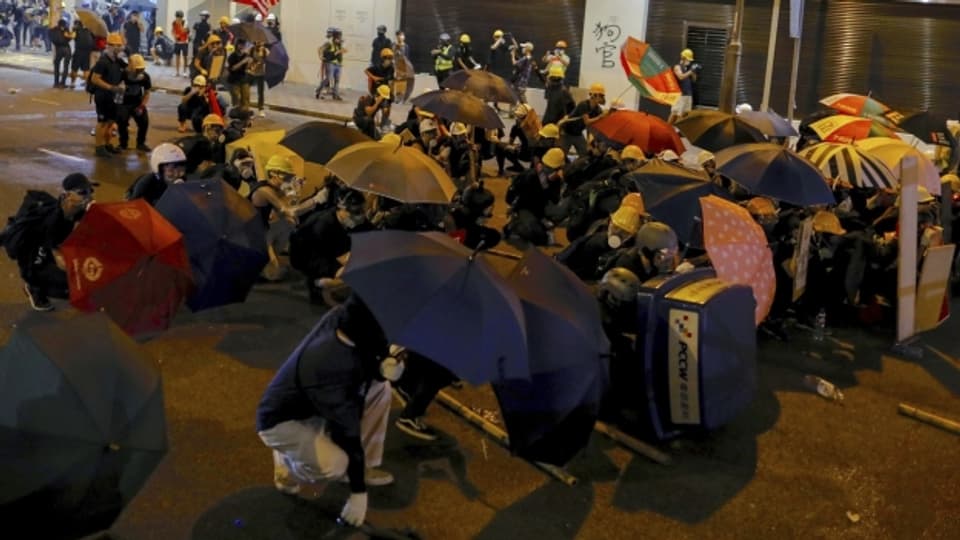Demonstranten in Hongkong schützen sich mit Regenschirmen gegen Tränengas