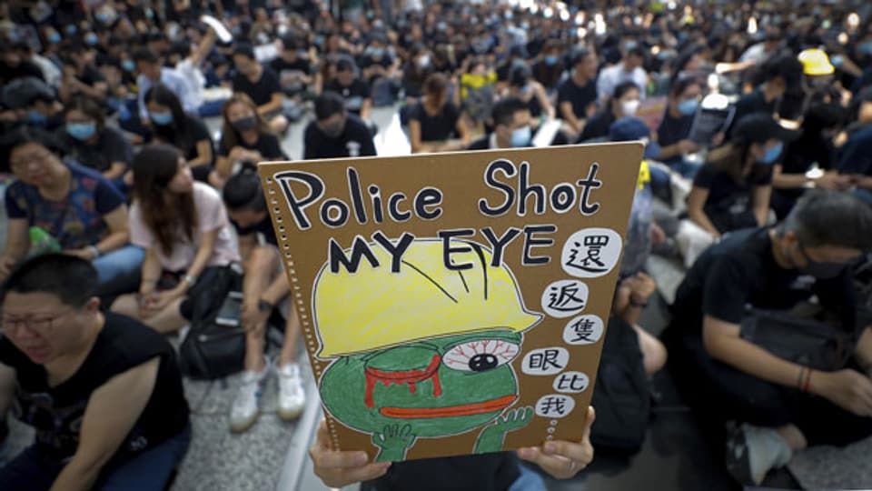 Ein Demonstrant am Flughafen von Hongkong hält ein Plakat in die Höhe.