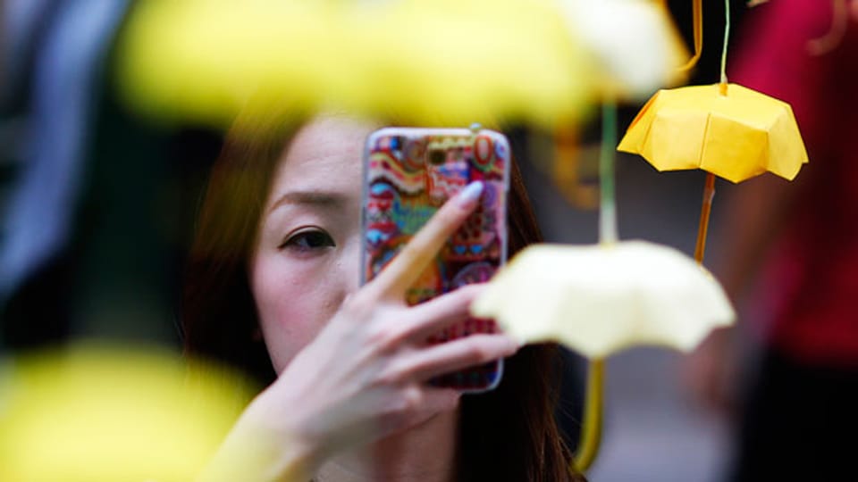 Eine Frau fotografiert mit ihrem Mobile Miniatur-Papierschirme, das Symbol der pro-demokratischen Demonstranten in Hongkong.