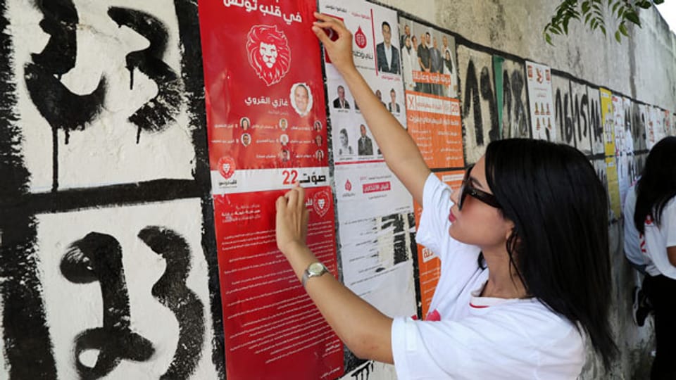 Anhängerin von Kalb Tounes (Das Herz Tunesiens) klebt ein Wahlkampagnenplakat vor den Parlamentswahlen in Tunesien.