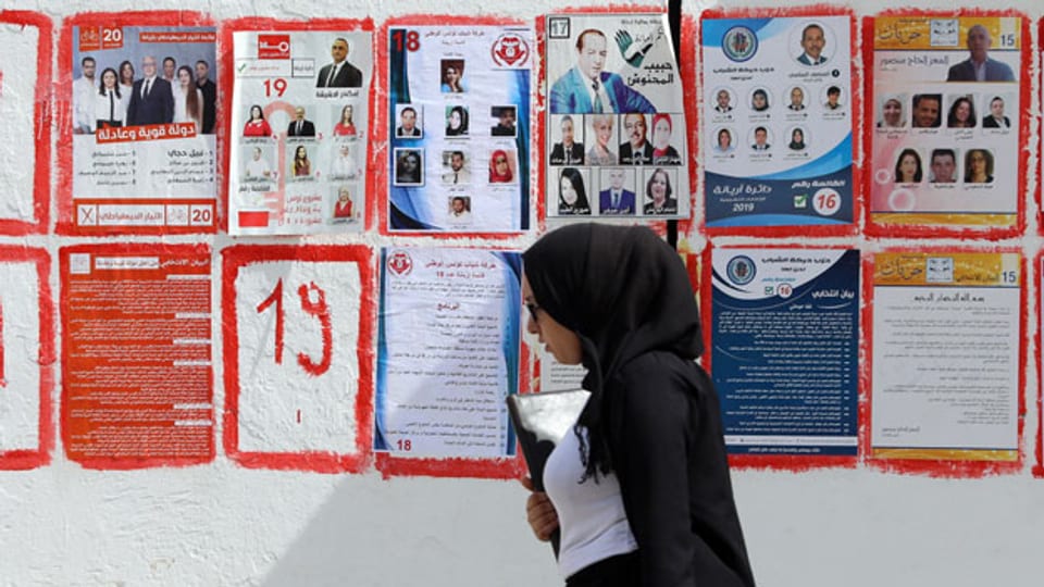 Eine Tunesierin geht an Listenplakaten für die bevorstehenden Parlamentswahlen in Tunis, Tunesien, 26. September 2019, vorbei.