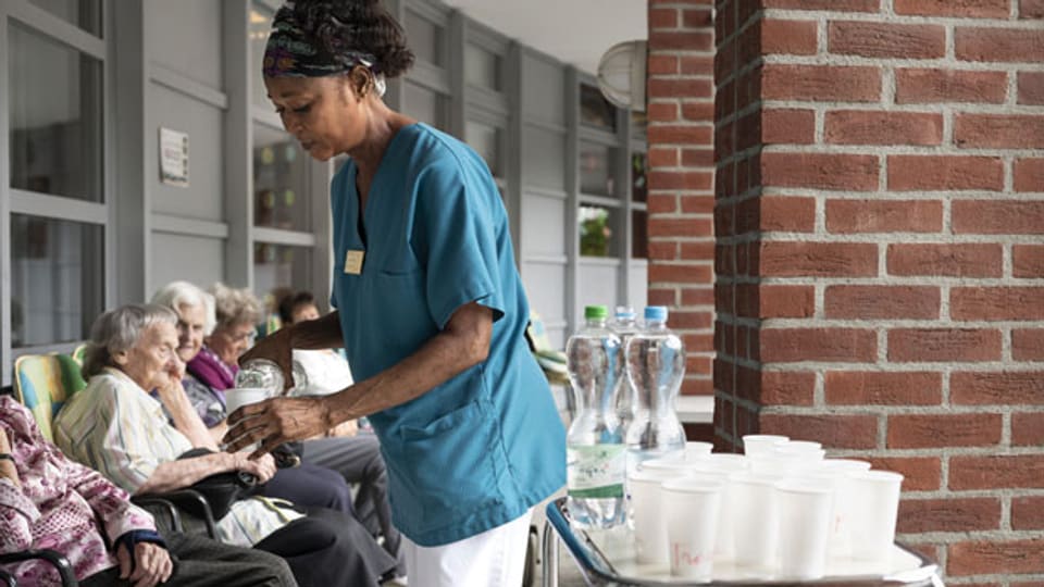 Eine Pflegefachfrau verteilt Wasser an die Bewohner und Bewohnerinnen eines Alterszentrums.